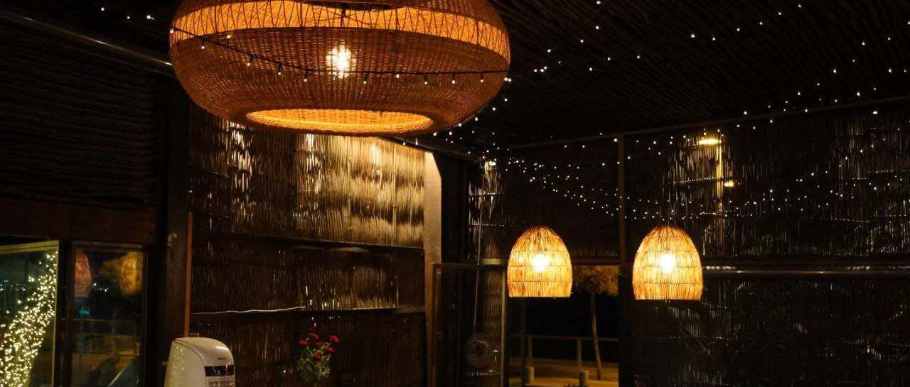 A terrace at night lit by woven lanterns and strings of small lights