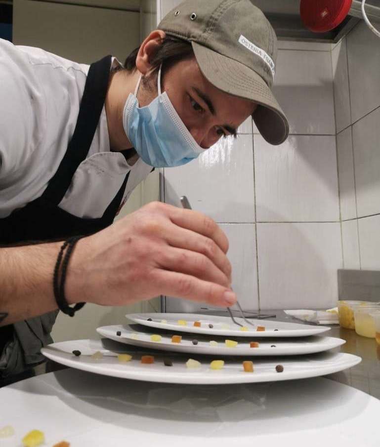 Ο Ευγένιος Χαραλάμπους τοποθετεί μικρά στοιχεία σε μια σειρά από πιάτα