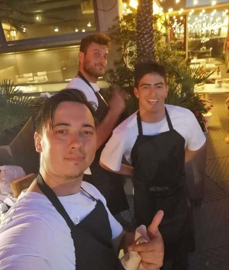 Eugene Charalampous with two colleagues in aprons on a restaurant terrace in the evening