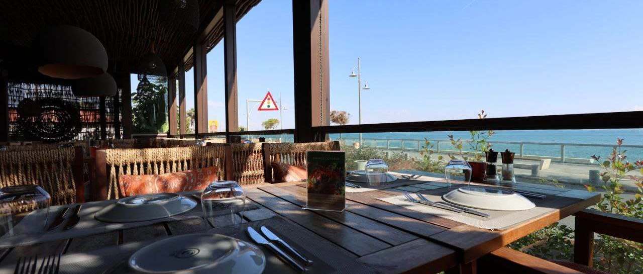 A table set on a covered terrace looking out over the sea on a clear day